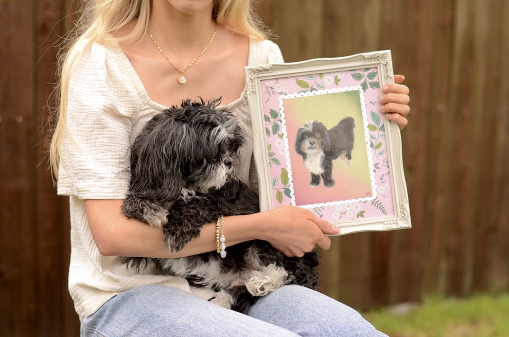 A dog looking at his own framed oil pastel portrait